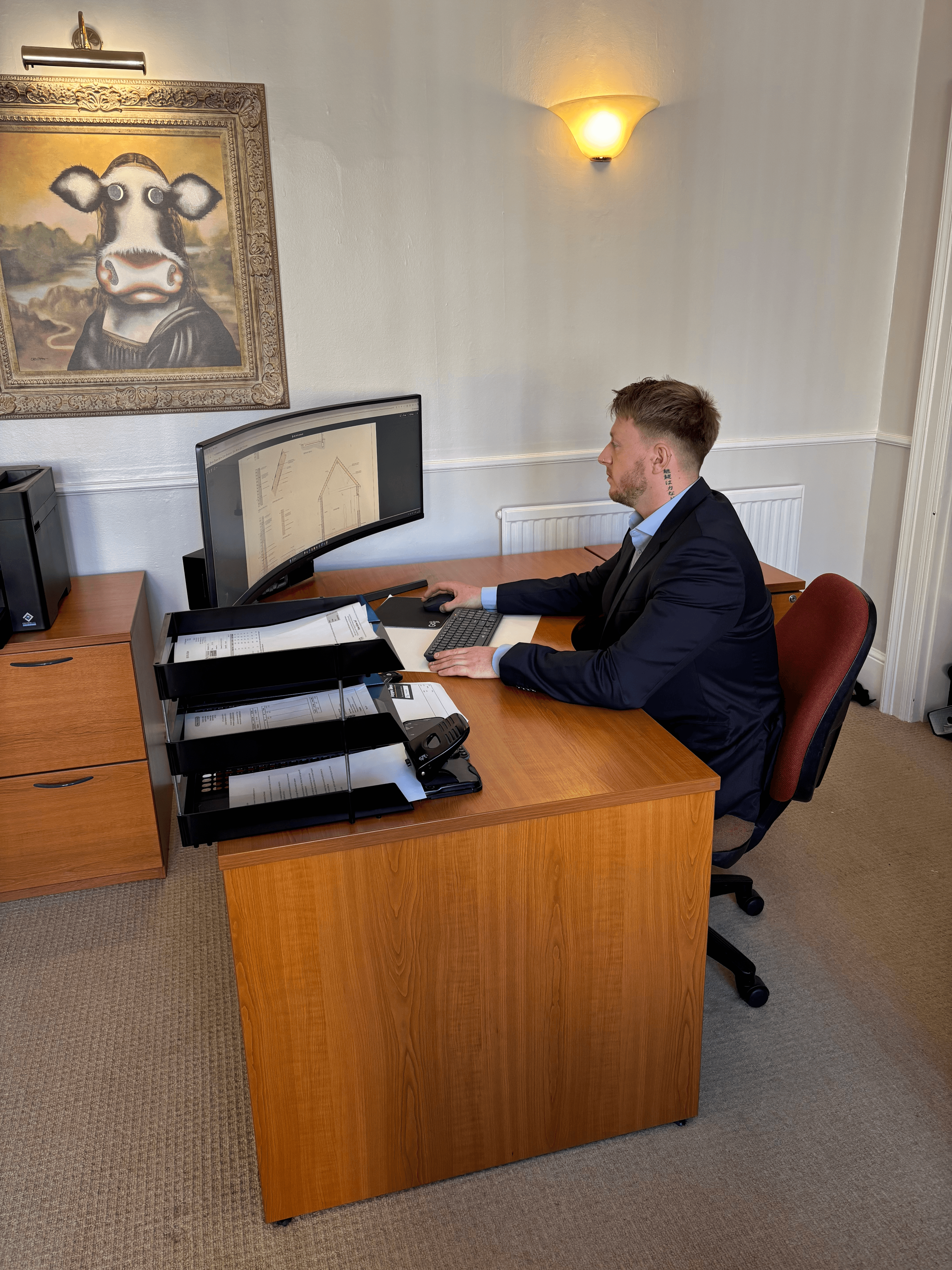 photo of a smartly dressed man reviewing technical drawings on a computer